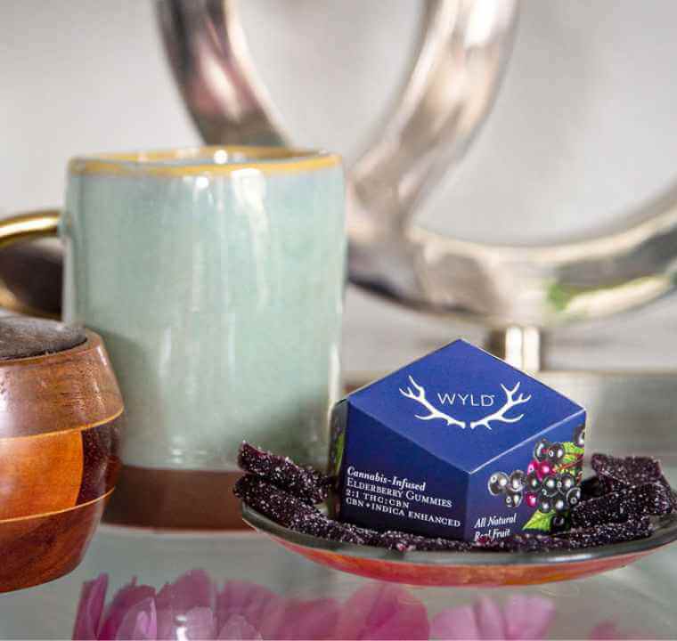 A pack of CBN Elderberry Wyld Gummies on a person's nightstand for an easy night's sleep.
